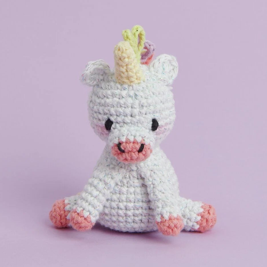 Crocheted unicorn toy on a light purple background