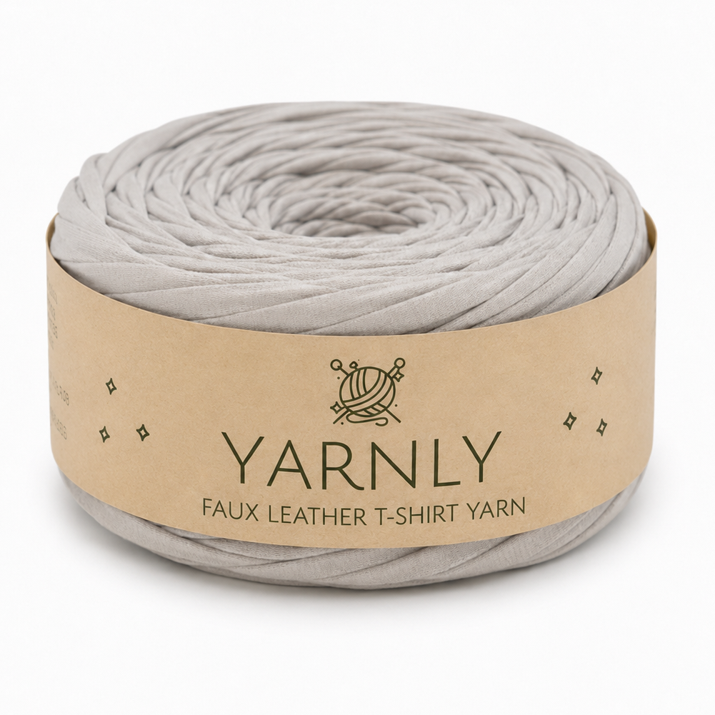 A roll of Yarnly faux leather T-shirt yarn in a light gray color, wrapped in a kraft paper band with the brand name 'YARNLY' printed on it, set against a plain white background.