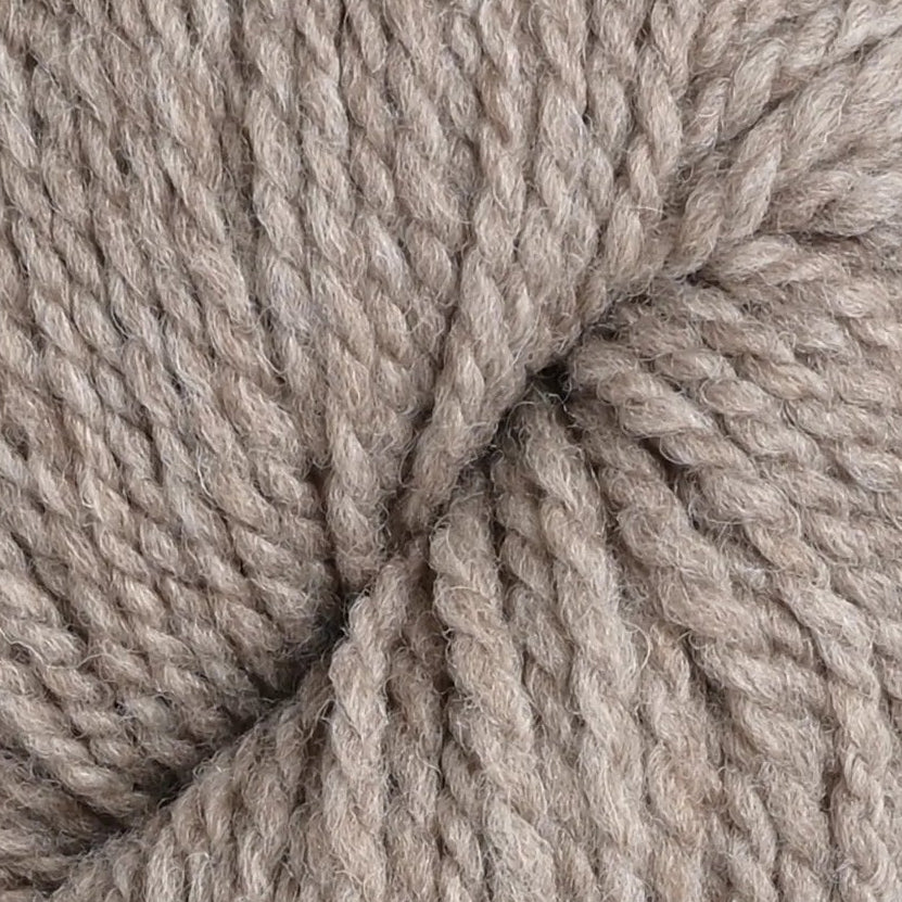 A skein of thick, twisted wool yarn in a warm taupe-gray color, photographed vertically against a textured white fabric background.